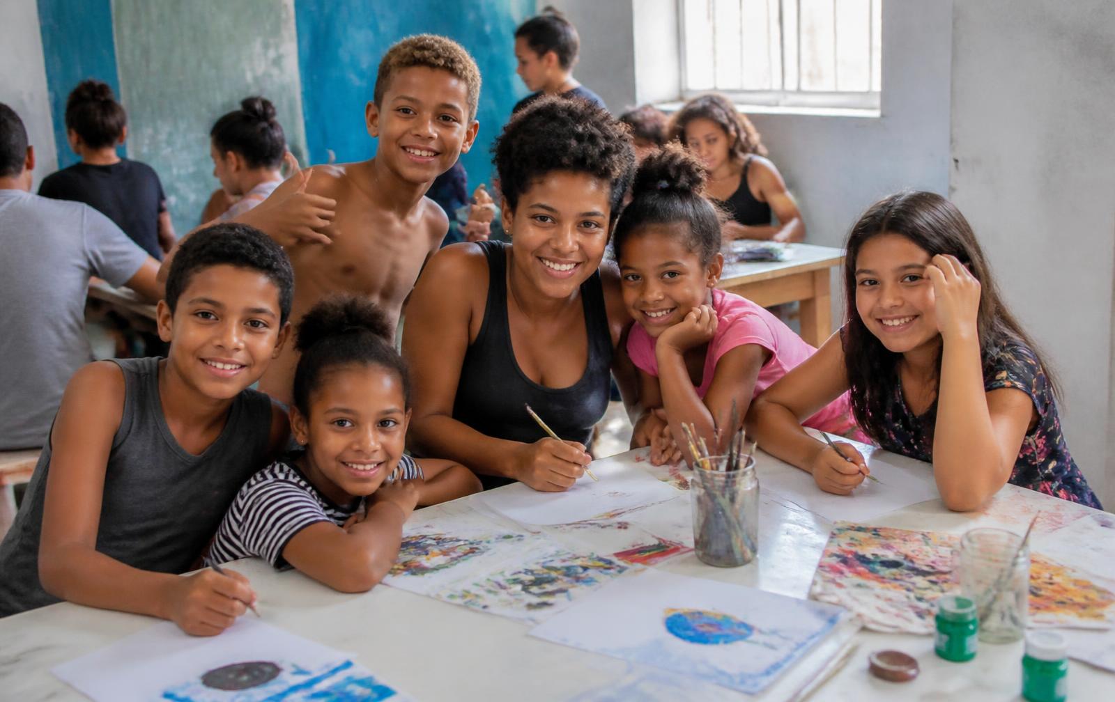 Crianças e adolescentes participando de uma oficina de arte com uma educadora